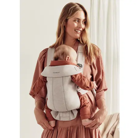 Smiling mother wearing her baby in a front-facing BabyBjörn carrier